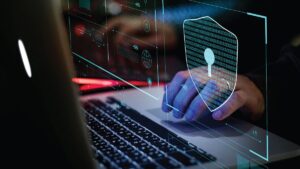 A close-up of a laptop with a blue glowing shield graphic, representing online security, data privacy, or cybersecurity measures.