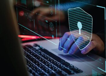 A close-up of a laptop with a blue glowing shield graphic, representing online security, data privacy, or cybersecurity measures.