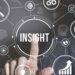 A conceptual image representing business insights, with a finger pointing to the central word surrounded by icons like a magnifying glass, target, and graphs.
