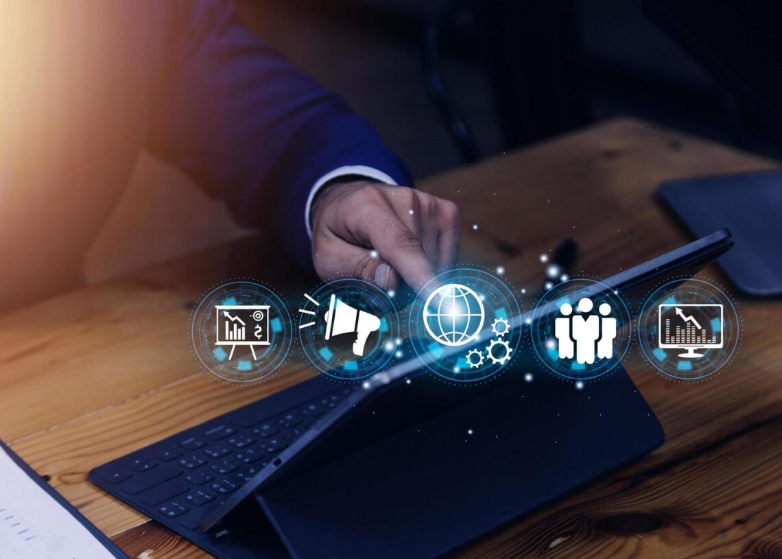 A professional interacting with a tablet that shows a visual representation of various business concepts such as marketing, global reach, teamwork, and data analytics.