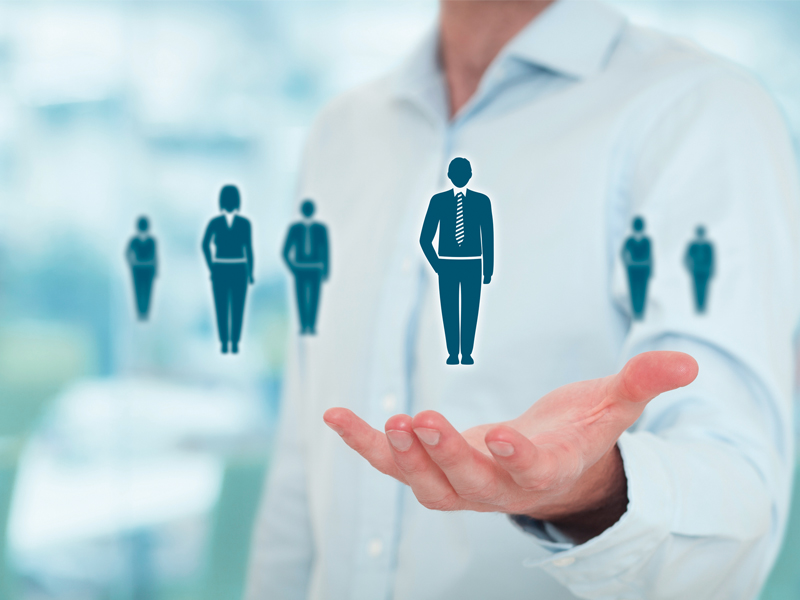 A visual metaphor for finding or managing personnel, featuring a detailed human silhouette being supported by an open hand, with a shallow depth of field.