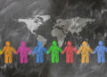 A visual representation of global unity and collaboration, showing stylized people in various colors holding hands beneath a world map on a textured dark surface.